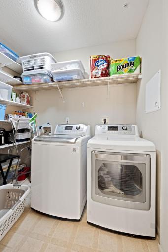 Large laundry room with side-by-side washer and dryer plus generous storage shelving.