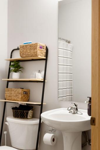 Stylish bath detail featuring a pedestal sink, tall mirror, and added storage.