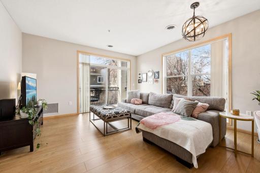 Bright living room with large windows, open layout, and access to the private balcony.