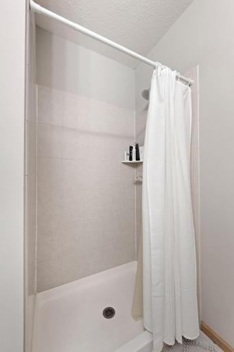Walk-in shower in the private primary bath with neutral tile finishes.