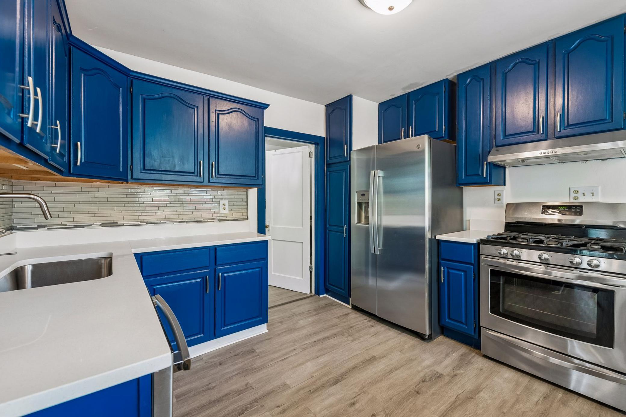 Sleek and modern kitchen updated in 2023 with white quartz countertops, sink, painted cabinetry and new hardware, LVP flooring and a fresh coat of paint in 2026.
