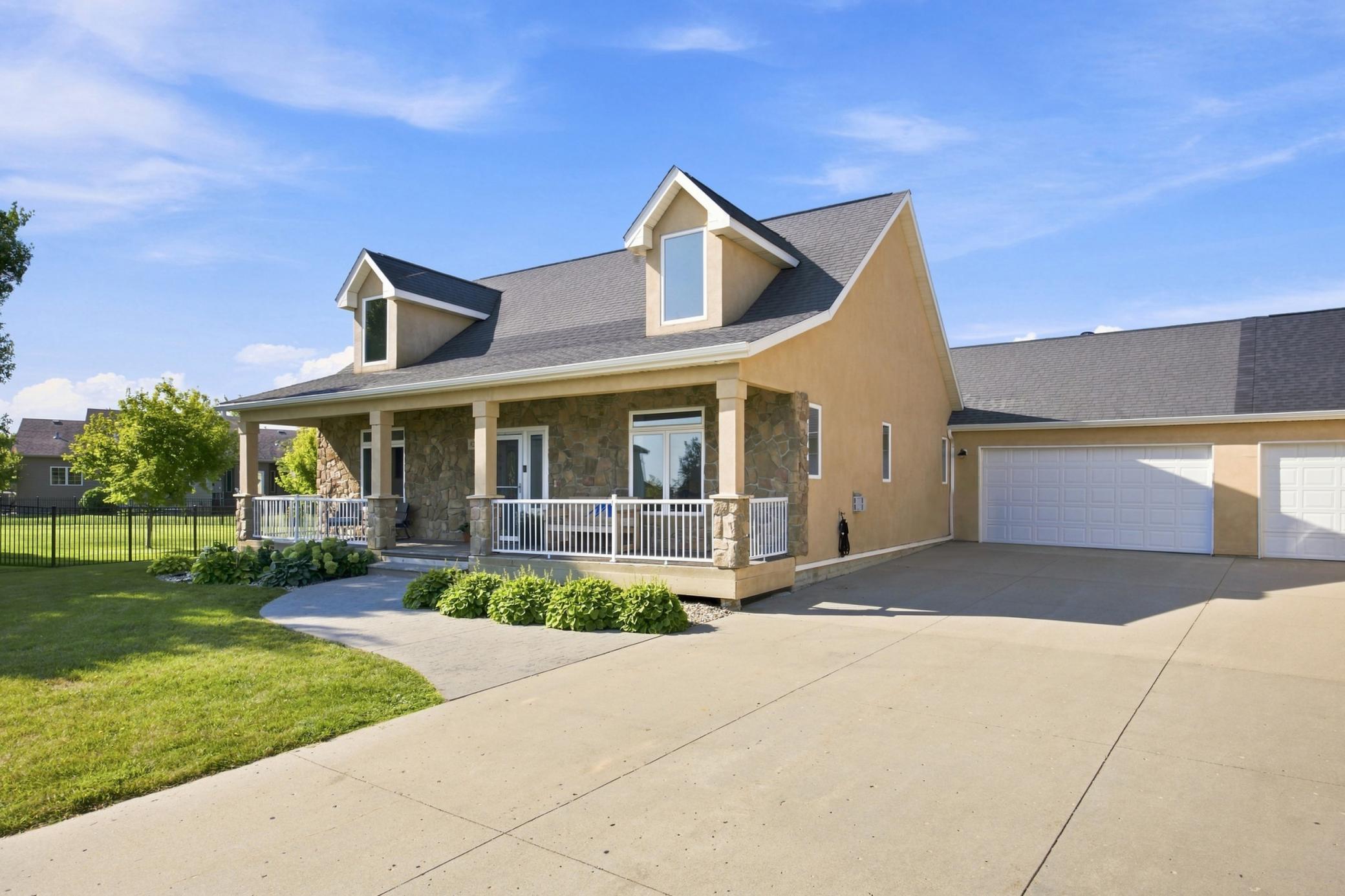 Beautiful curb appeal with perennials leading up to covered front porch with stone accents; 2-stall attached finished garage; lots of additional parking.