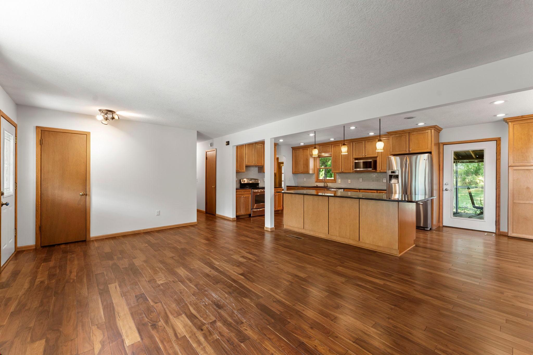 Step into a completely open main level where timeless hardwood floors connect the living, dining, and kitchen spaces.