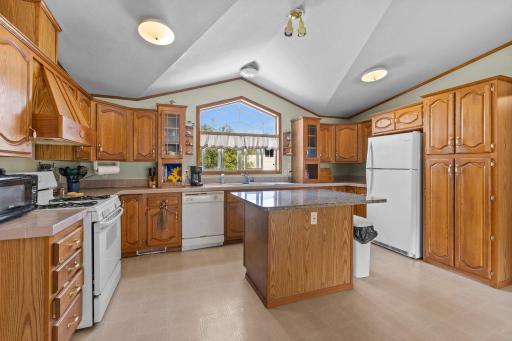 Spacious kitchen with tall ceilings, large window, gas stove and ornate vent-hood