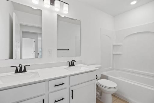 This shared full bathroom features dual sinks and a shower-tub combination.