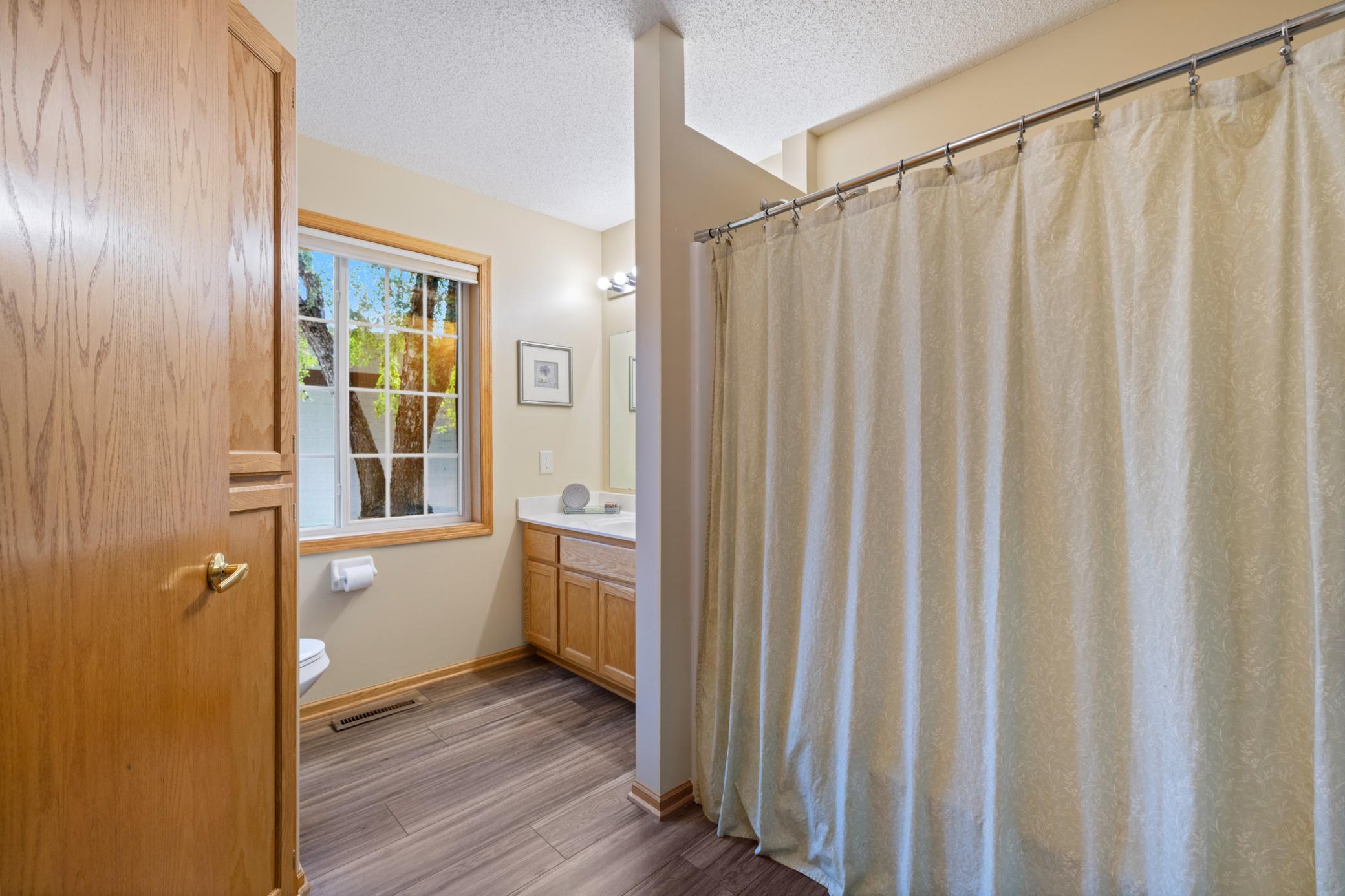 Guest bathroom has beautiful laminte flooring tub and large linen closet for storage.