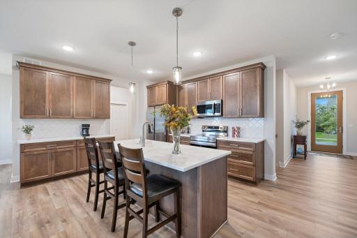 Rich brown cabinetry, luxury vinyl plank flooring, gorgeous marble counters and large center island make this the focal point in this open floor plan.