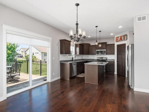 Gourmet kitchen with rich espresso cabinetry, stainless steel appliances, a center island, and convenient access to the outdoor deck, ideal for indoor/outdoor entertaining.