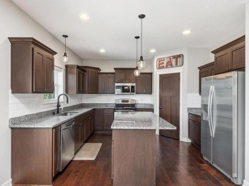 Chef's dream kitchen featuring granite countertops, abundant cabinet storage, a large center island, stainless steel appliances, and stylish pendant lighting.
