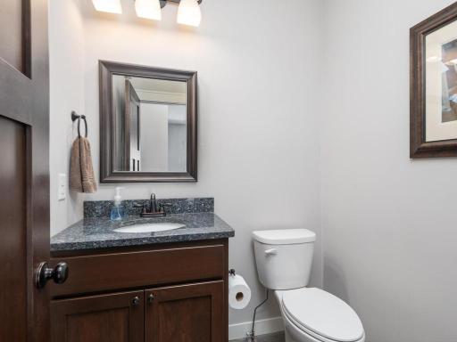 Stylish main floor 1/2 bathroom featuring granite countertop, custom vanity with rich wood cabinetry, and elegant finishes.