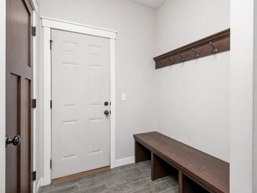 Practical mudroom with built-in bench seating, coat hooks, and tile flooring.