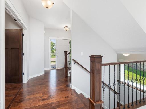 Impressive upper-level foyer with soaring vaulted ceilings, elegant wrought iron staircase railing, and abundant natural light throughout.
