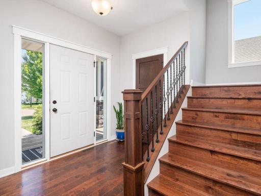 Stunning staircase with rich hardwood treads and decorative iron balusters leads to the spacious upper-level living areas.