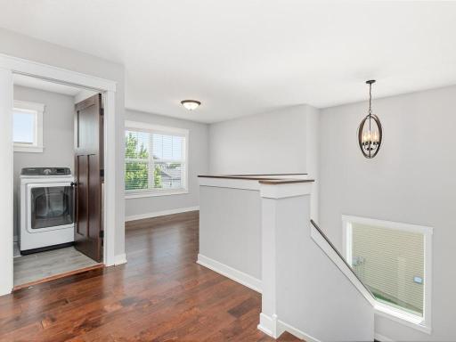 Convenient upper-level landing with laundry access and beautiful hardwood flooring.