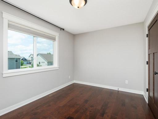 An additional spacious bedroom featuring hardwood floors, a large window with natural light, and neutral décor, ready for your personal style.