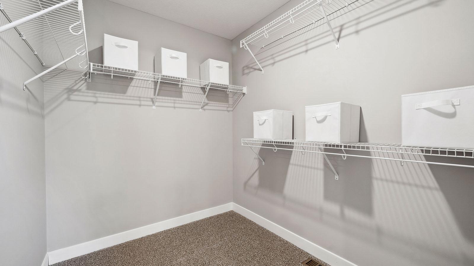 One of two walk-in closets in the primary suite. Photo of model home, colors and finishes may vary.