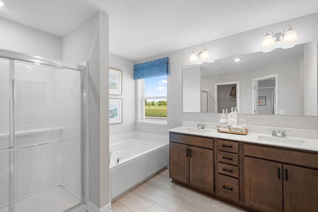 The luxurious en-suite bathroom features a walk-in shower, a relaxing soaking tub, dual sinks, and dual closets! Photo of model home, colors and finishes may vary.