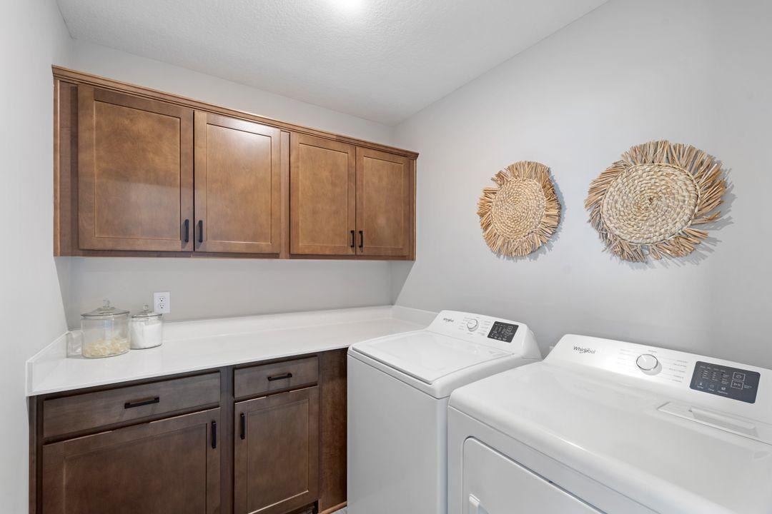 The upper level laundry room features cabinets to store all of your laundry essentials and a folding counter. Photo of model home, colors may vary.