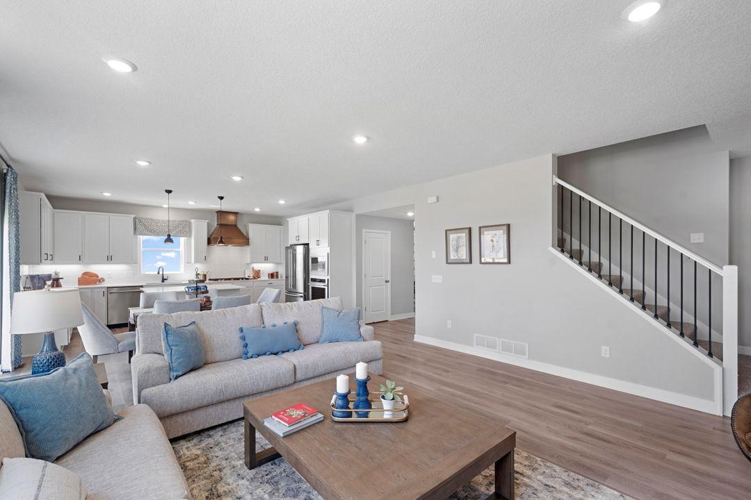 A view from the living room into the kitchen. This home will include the beautiful spindle stair rail. Photo of model home, colors and finishes may vary.