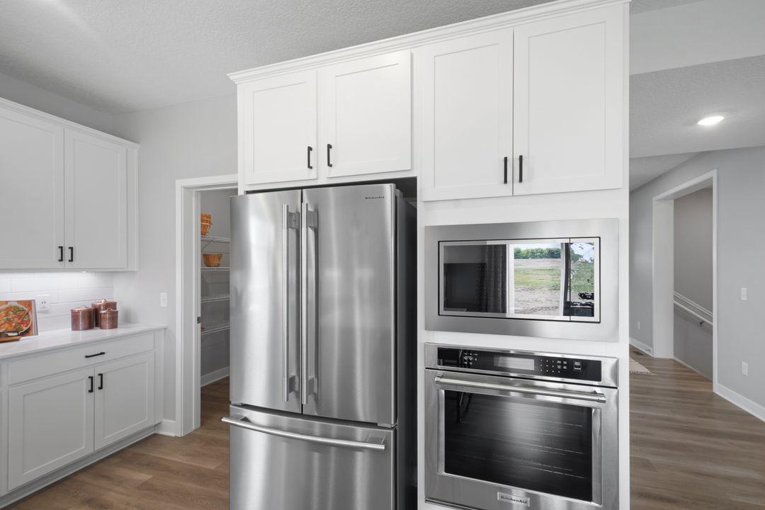 Here you see the built in microwave and oven, the pantry to the left, and just around the corner you will find the main entry and front flex room. Photo of model home, colors and finishes may vary.