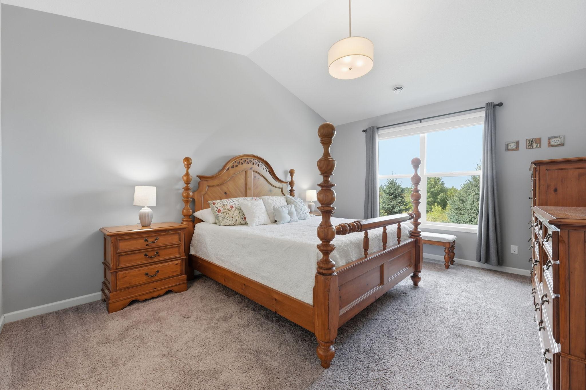 Primary suite with large windows and vaulted ceiling