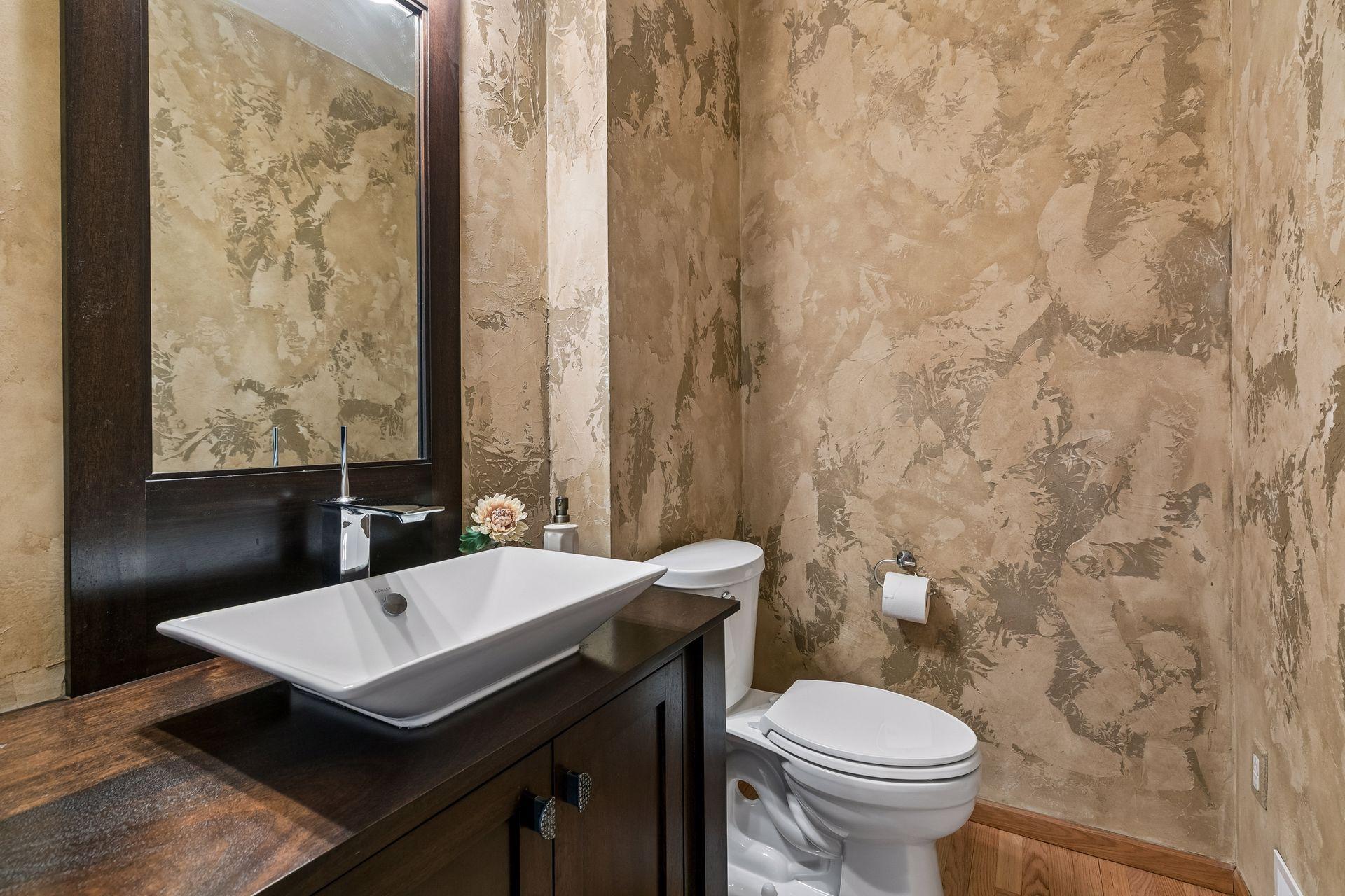 A beautifully designed main floor powder room featuring stylish wall treatments and an eye-catching vanity.