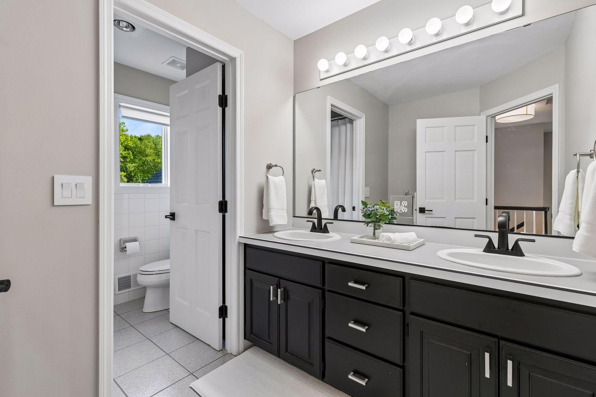 A full upper-level bathroom features a separate vanity area, allowing multiple people to use the space at the same time.