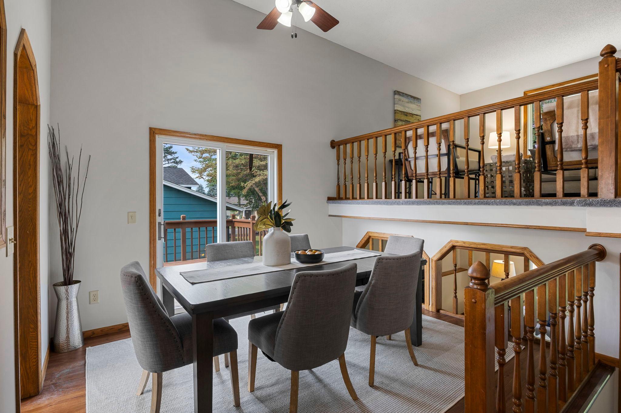 The kitchen opens directly to the dining room, which showcases vaulted ceilings, a modern hanging light fixture, and direct access to the 15x12 deck.
