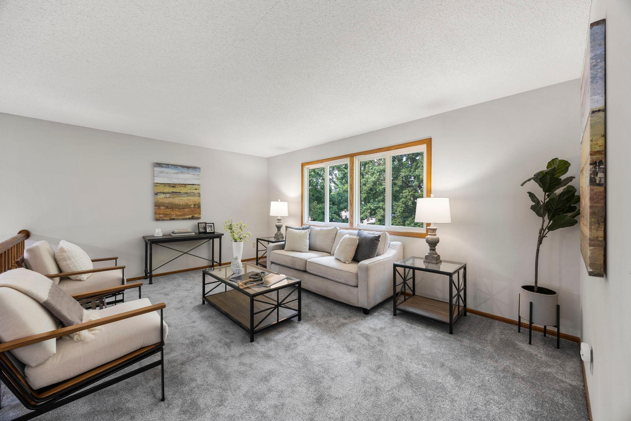 Upstairs, the spacious living room features a railing overlooking the dining area below, a large rear-facing window allowing for abundant natural light, and brand-new carpeting that extends throughout.