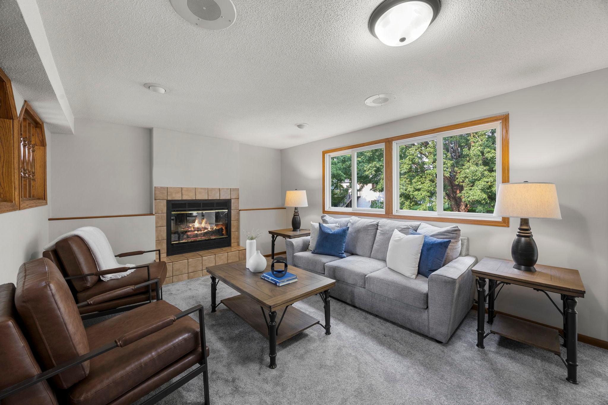 The lower level offers a spacious family room and recreation area featuring a cozy wood-burning fireplace, new carpeting, and walkout access to the backyard.