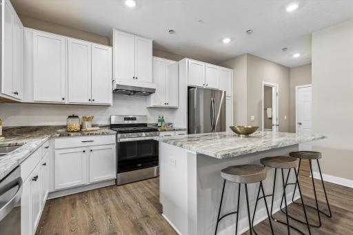 Center island Kitchen with granite countertops, white cabinetry, stainless steel appliances and recessed lighting.