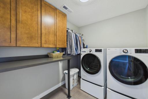 The upper-level laundry room was improved in recent years with a new cabinet/countertop system and place to hang clothes.