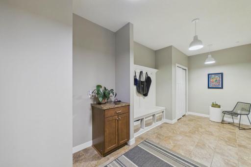The large mudroom with a built-in bench and coat hooks offers the perfect drop zone for busy households, keeping everything organized and tidy.