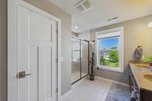 The primary bathroom offers a spa-inspired ensuite with a walk-in shower, double vanity sinks, and tiled flooring!