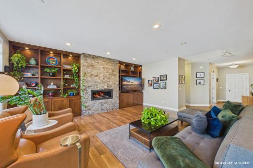 As you enter the home you are immediately greeted with a spacious living room featuring a stunning custom entertainment system paired with a gas fireplace framed by a dramatic floor-to-ceiling stone surround.
