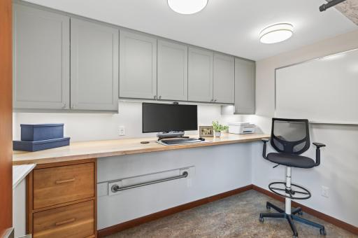 Dedicated home office with extensive built-in cabinetry, workspace and whiteboard.