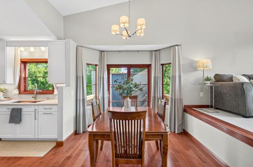 Dining area with hardwood floors, vaulted ceiling and windows on three sides, including direct access to the outdoor deck.