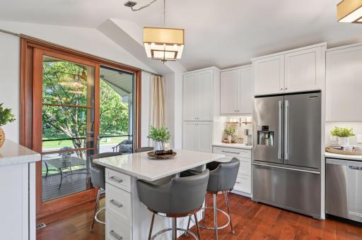 Bright kitchen with white cabinetry, quartz countertops, stainless steel appliances, center island seating and abundant storage.