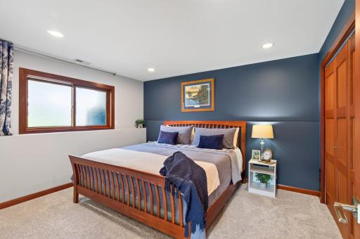 Comfortable lower-level 4th bedroom with generous closet space and warm wood trim.
