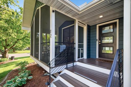 Covered front entry conveniently located next to the three-car garage, with composite steps, modern cable railings and access to the screened porch which extends the living space outdoors while overlooking the landscaped yard.