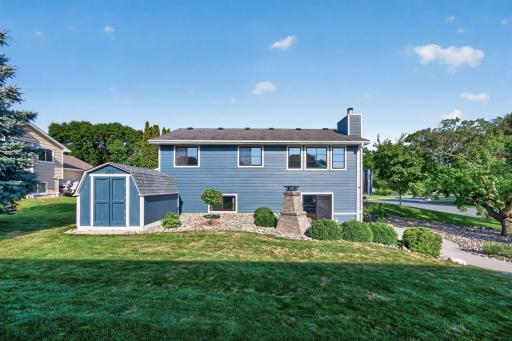 Rear exterior view highlighting the landscaped yard, storage shed and lower-level walkout access.