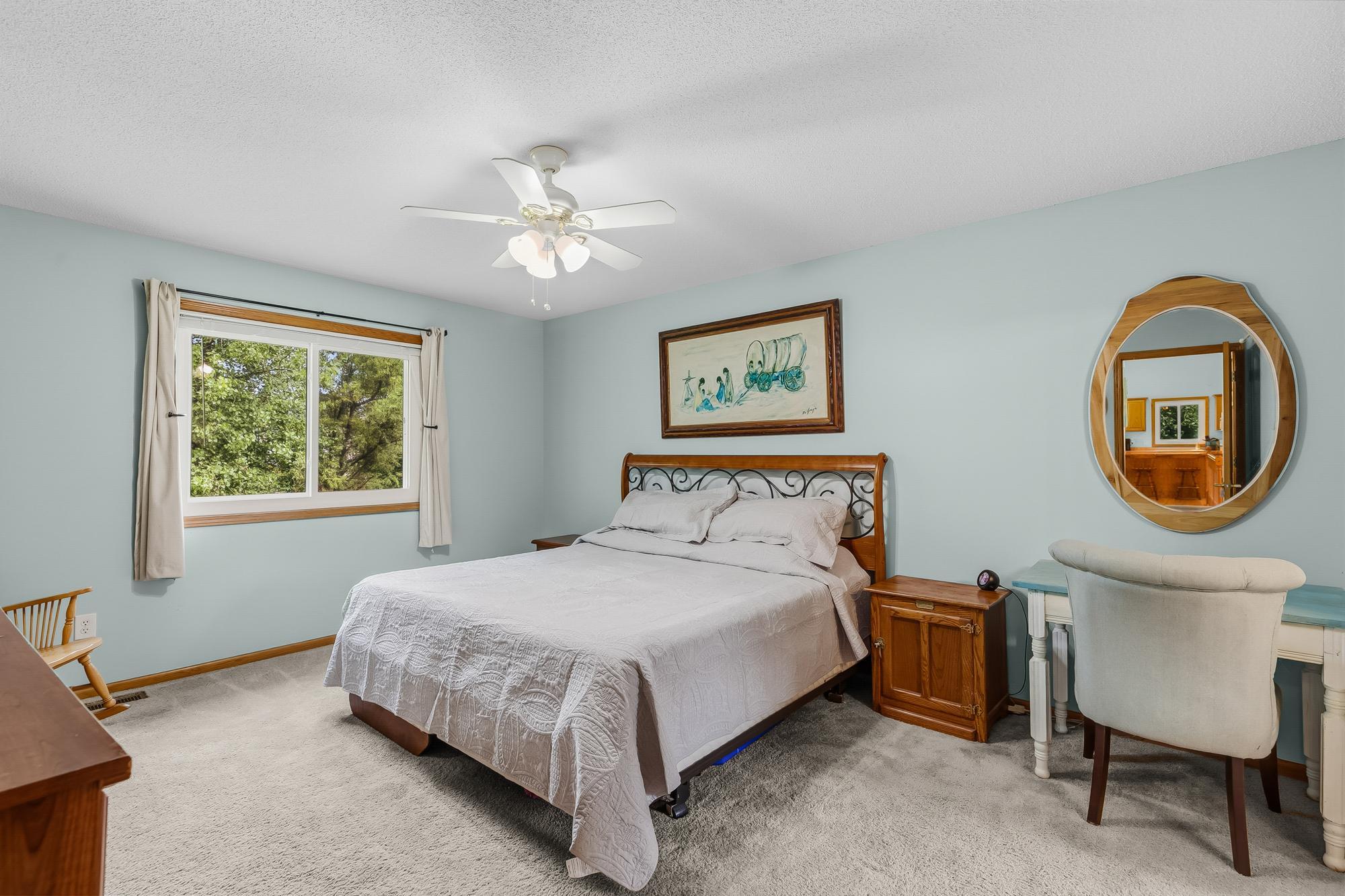 The spacious main-floor primary bedroom offers a relaxing retreat with a large window and great natural light.