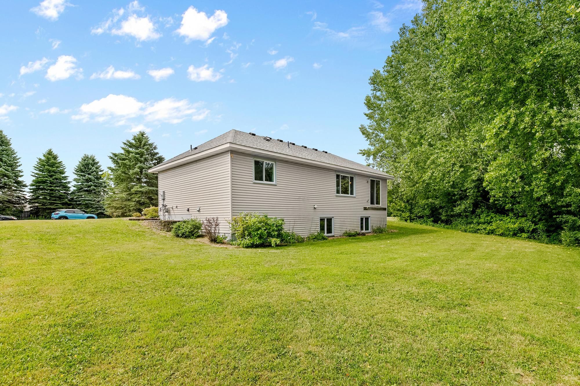 A view of the rear exterior, highlighting the home's lower-level daylight windows and massive green space.