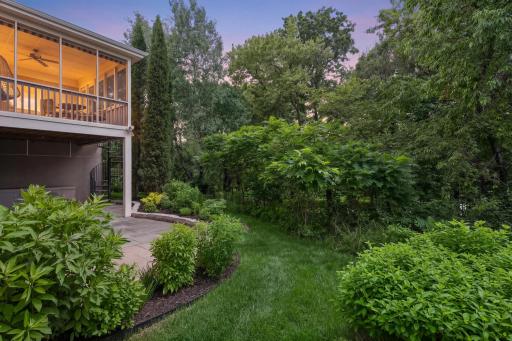 Screened porch glowing above a private walkout patio