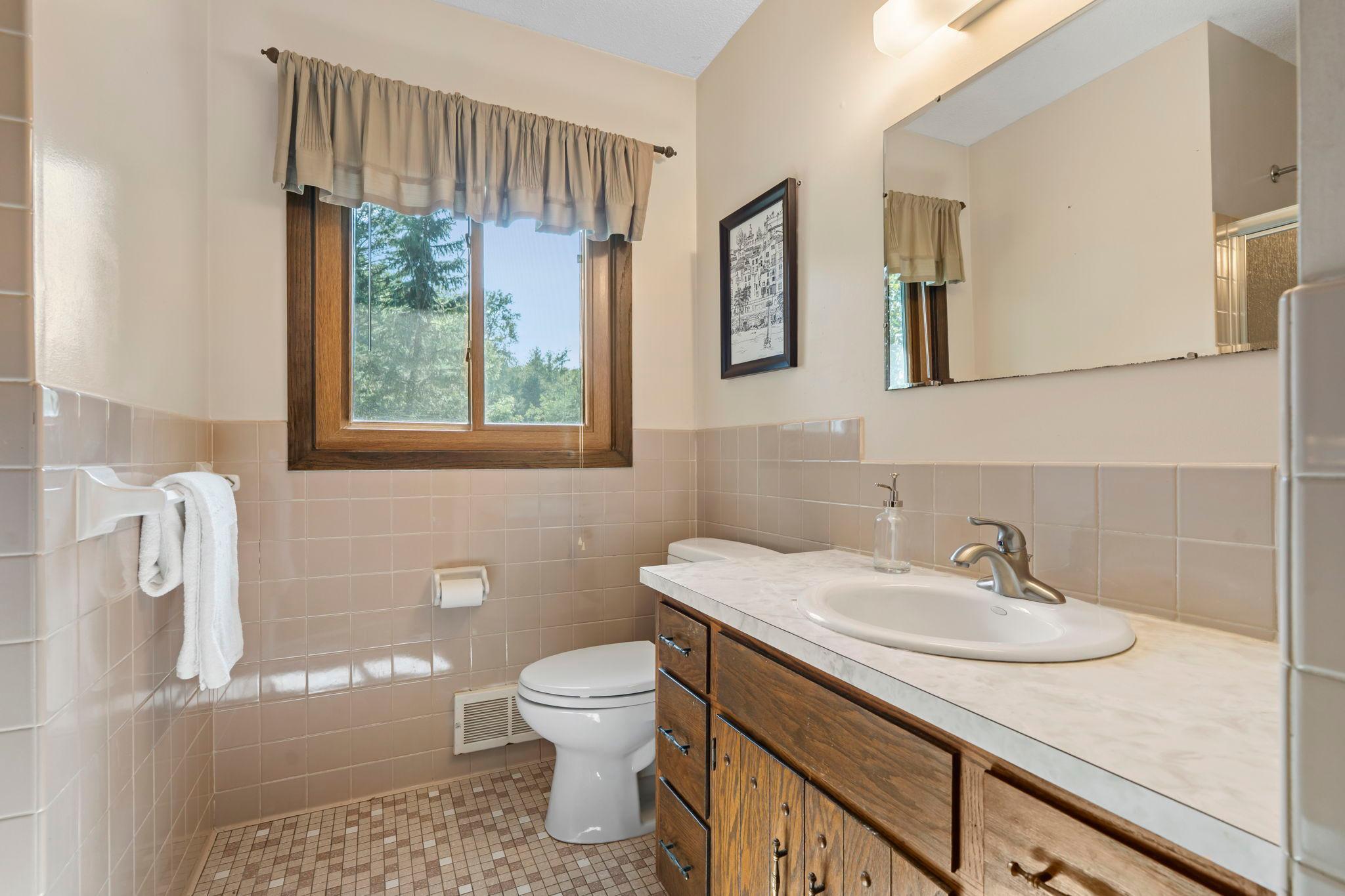 Full bathroom with stunning tile surround accent on the walls serving the main level.