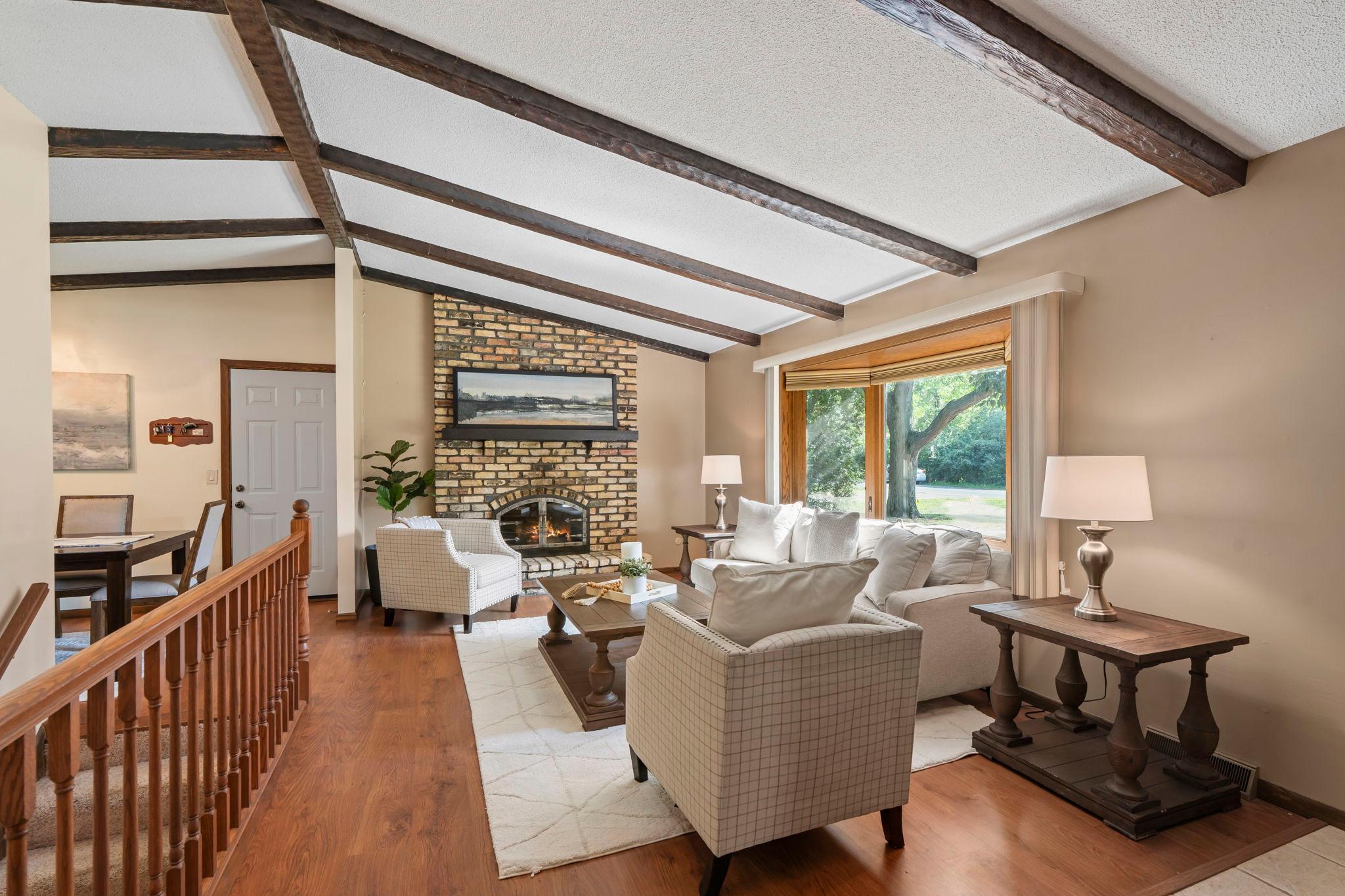 Hardwood floors and vaulted ceilings with wood beams and a beautiful brick surround fireplace.