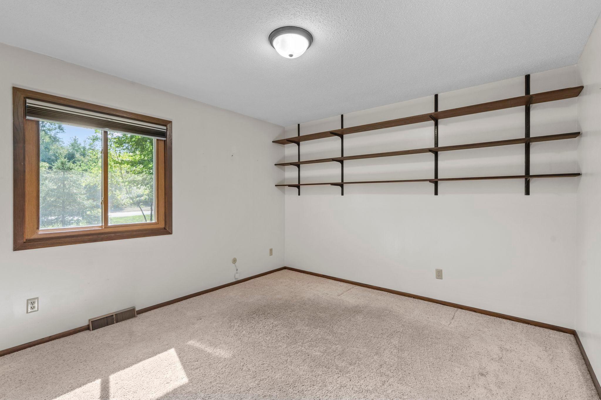 Third bedroom on the main level overlooking the front yard with wooden shelves.