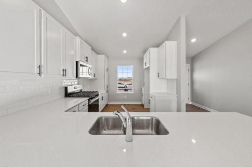 Gleaming quartz countertops with classic subway tile backsplash. Photo is of similar home. Colors and options may vary. Ask Sales Agent for details.