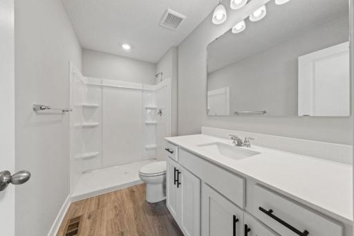 A peak inside the bathroom off the Primary Suite. Notice the extra high cabinets and Quartz covered vanity with loads of storage! Photo is of similar home. Colors and options may vary. Ask Sales Agent for details.