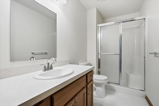 Lower level ¾ Bathroom features with tile floor, oak vanity and updated light fixture
